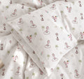 White bedding set with a whimsical giraffe and palm tree print, including a duvet cover and matching pillowcases.